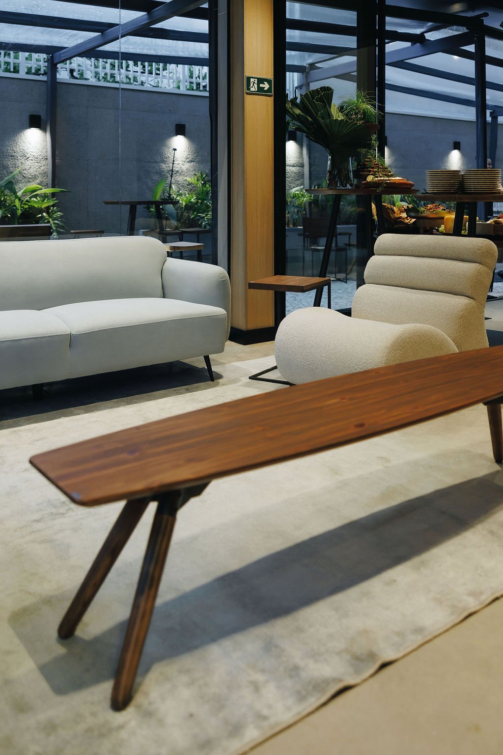 Sofá, banco de madeira maciça e poltrona em ambiente montado na flagship Studio Madeira