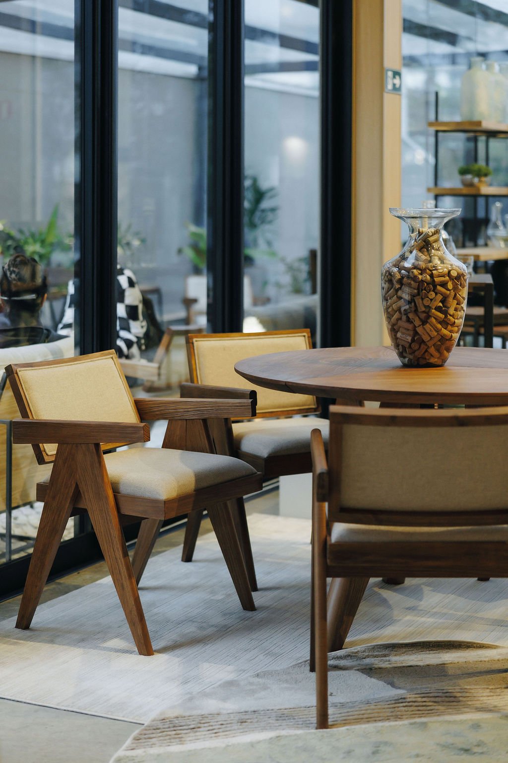 Mesa de jantar redonda de madeira maciça com cadeiras de palha na flagship Studio Madeira